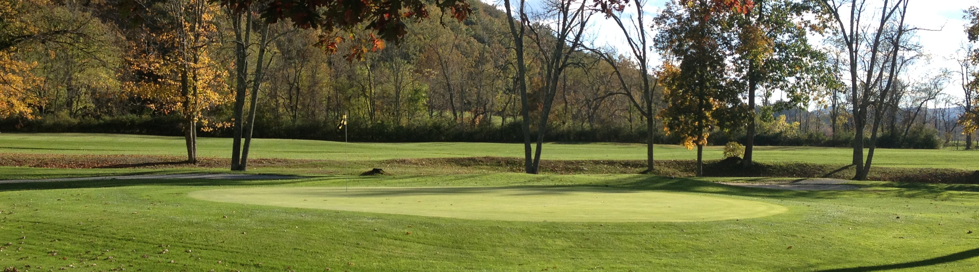 View of a hole with a mountain in view in the background on the left and some barren trees on the right 